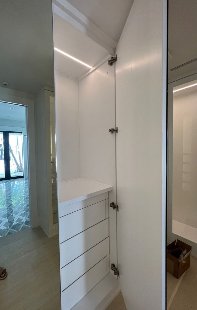 A white cabinet in a room with a mirror on the wall.