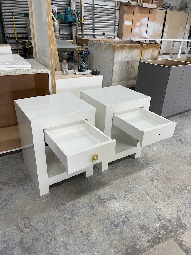 Two white nightstands with drawers open in a factory