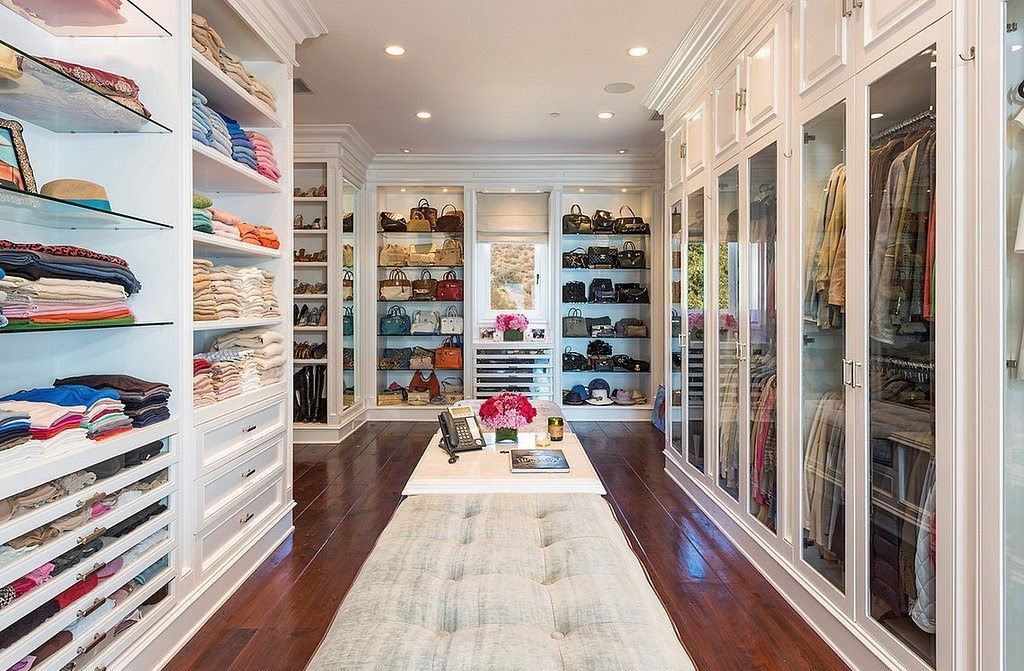 A large walk in closet filled with lots of clothes and shoes.