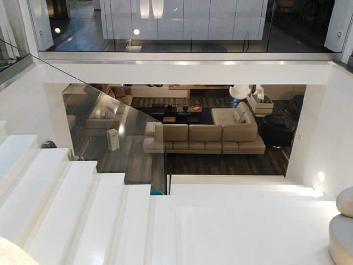 Vista da una scala bianca, con vista su un soggiorno moderno con un divano componibile beige.