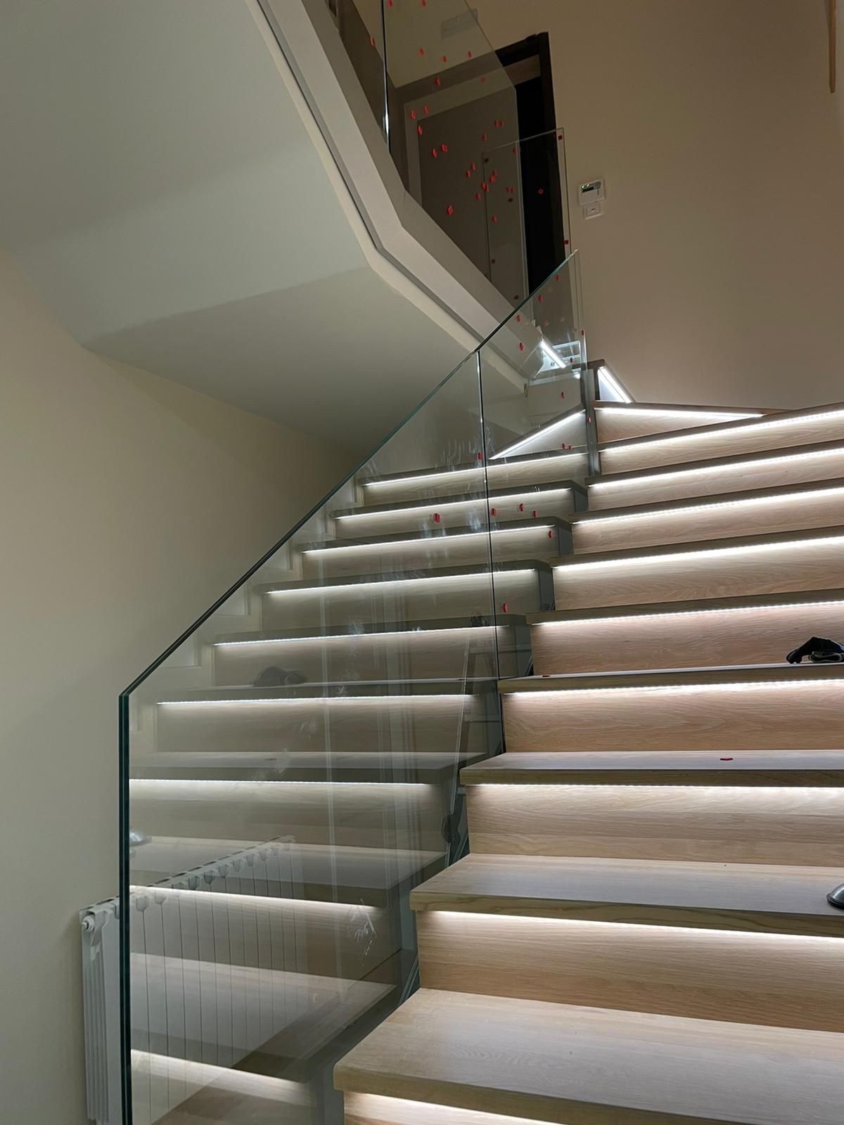 Scala moderna con ringhiera in vetro e gradini illuminati, in un interno ben illuminato.