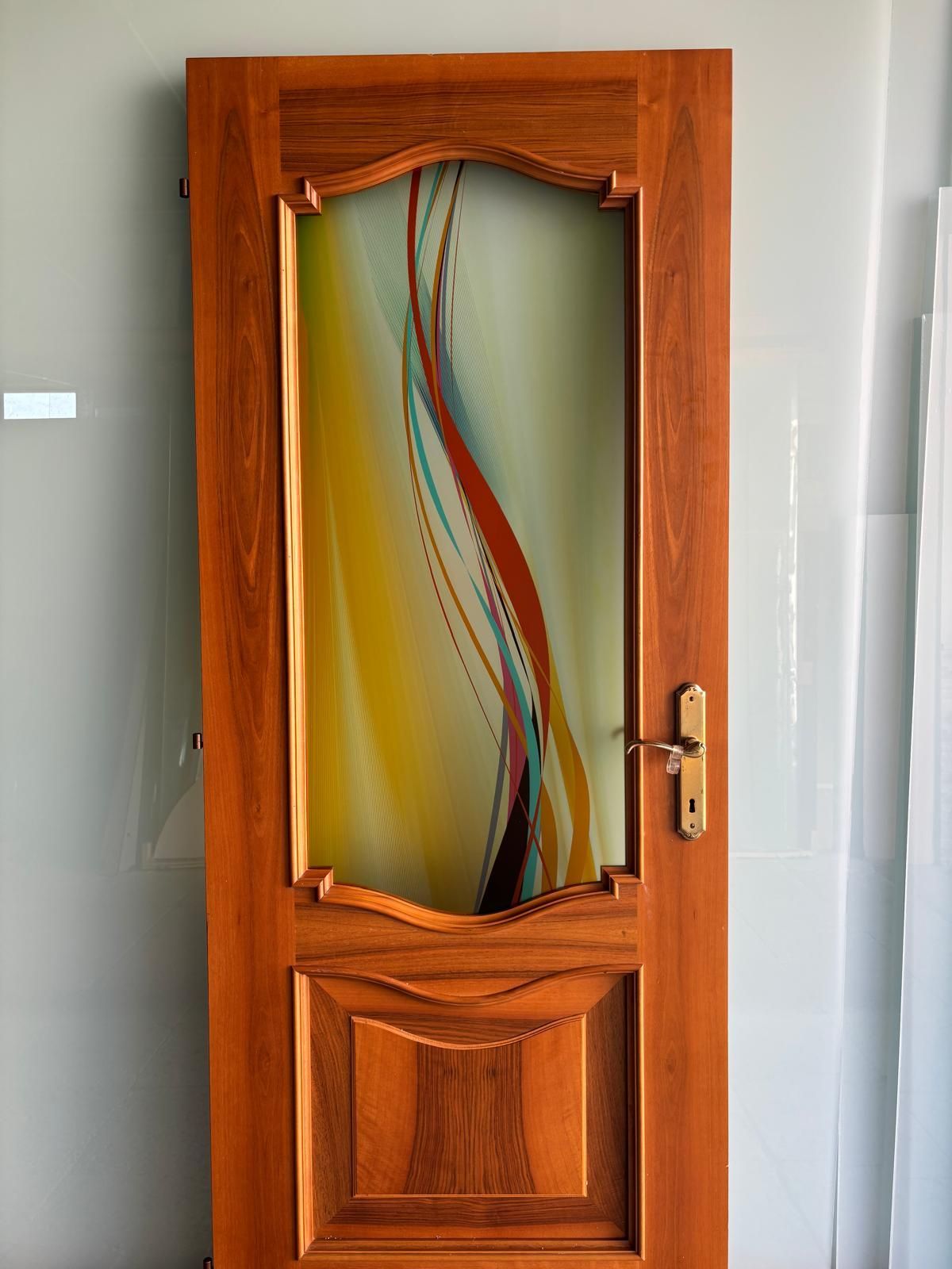 Porta in legno con pannello decorativo in vetro decorato con vortici astratti colorati.