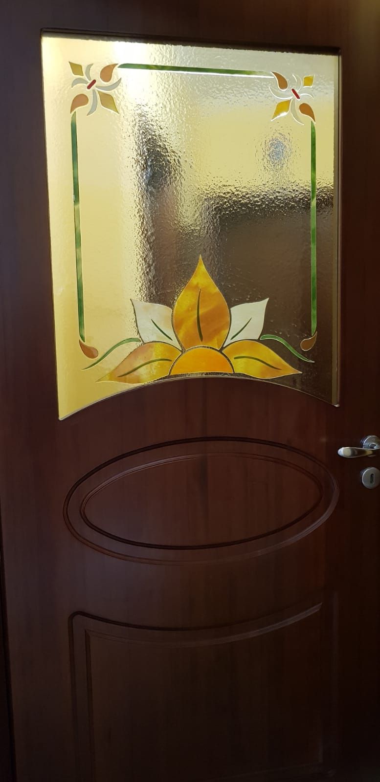 Porta in legno con pannello in vetro colorato raffigurante un fiore giallo e un bordo decorativo.