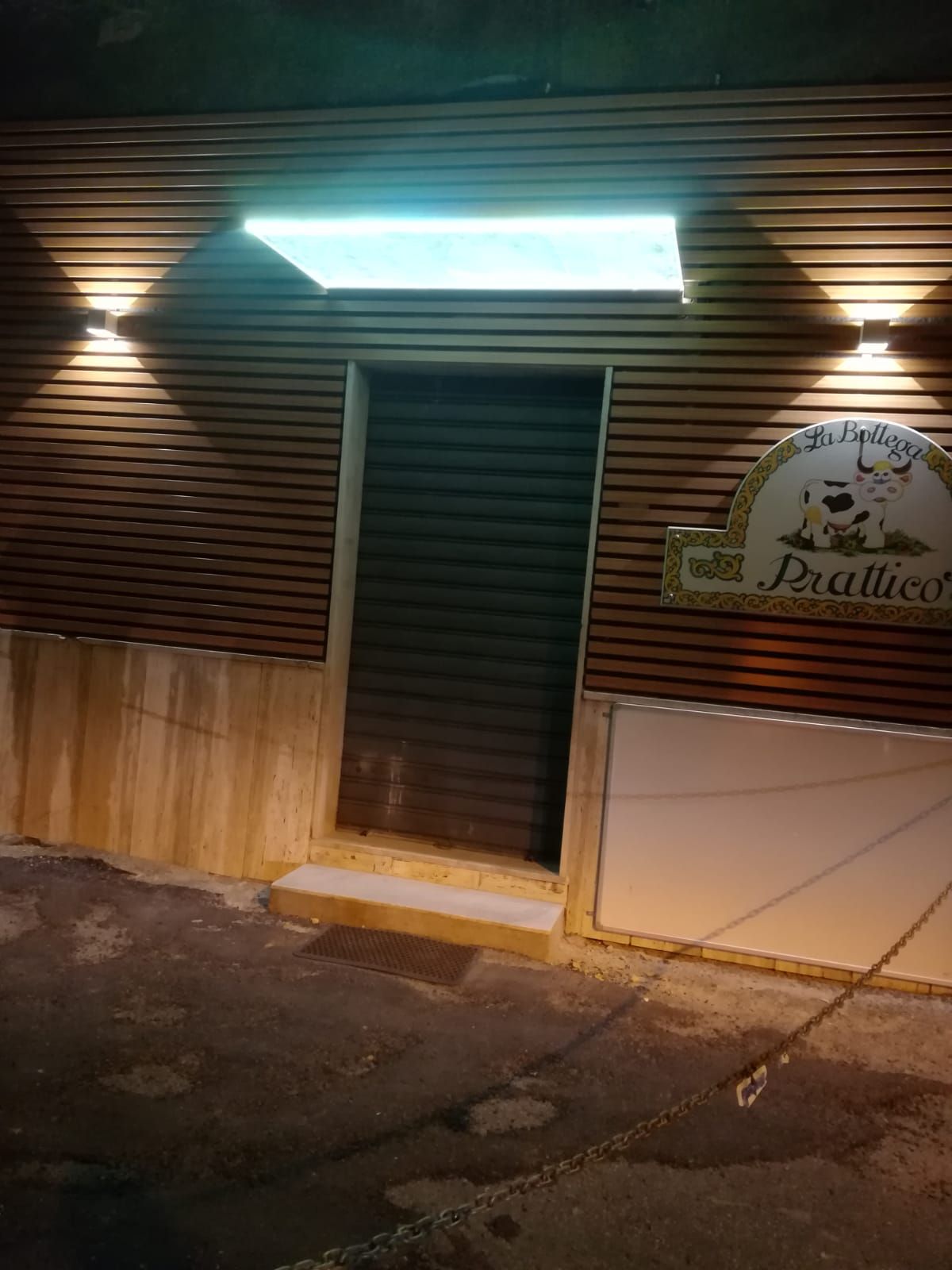 Ingresso di casa moderno con pensilina in vetro, porta in legno e facciata in pietra.