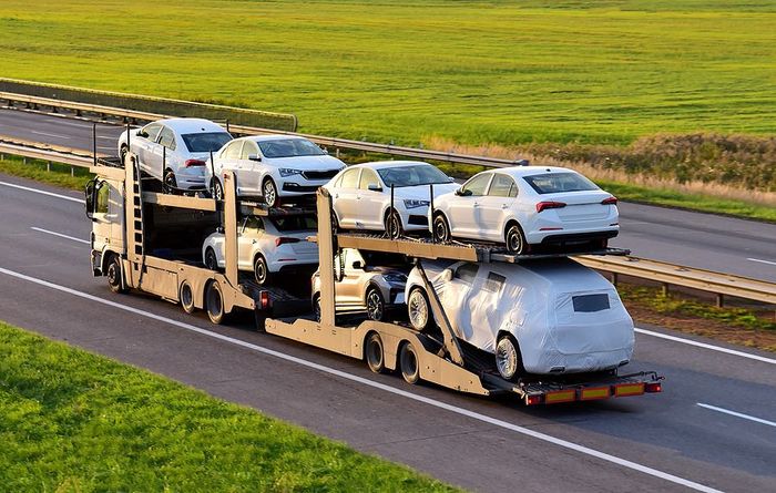 a semi truck carrying a car on the back of it