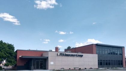 A large brick building with a blue sky and clouds in the background.