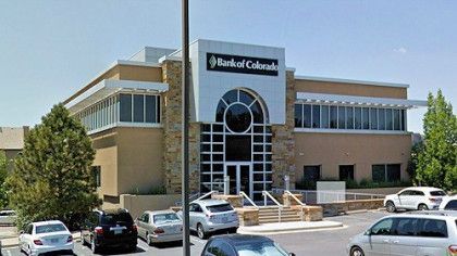 A bank of colorado building with cars parked in front of it.