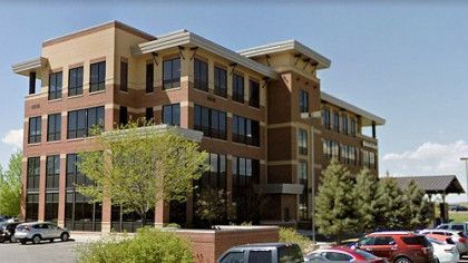 A large brick building with a lot of windows and cars parked in front of it.