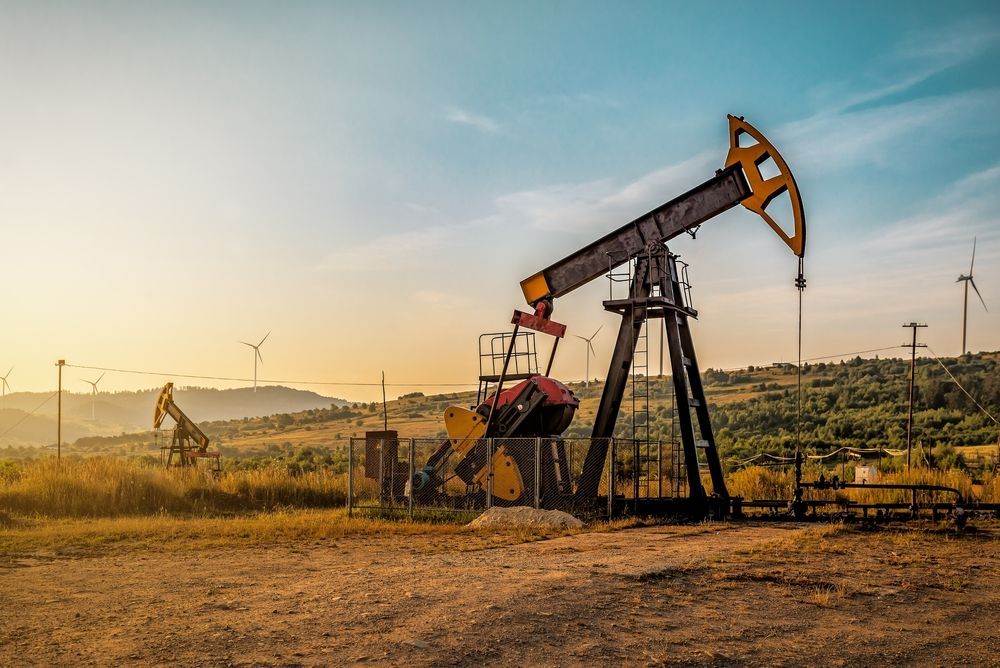 An oil pump is sitting in the middle of a field.