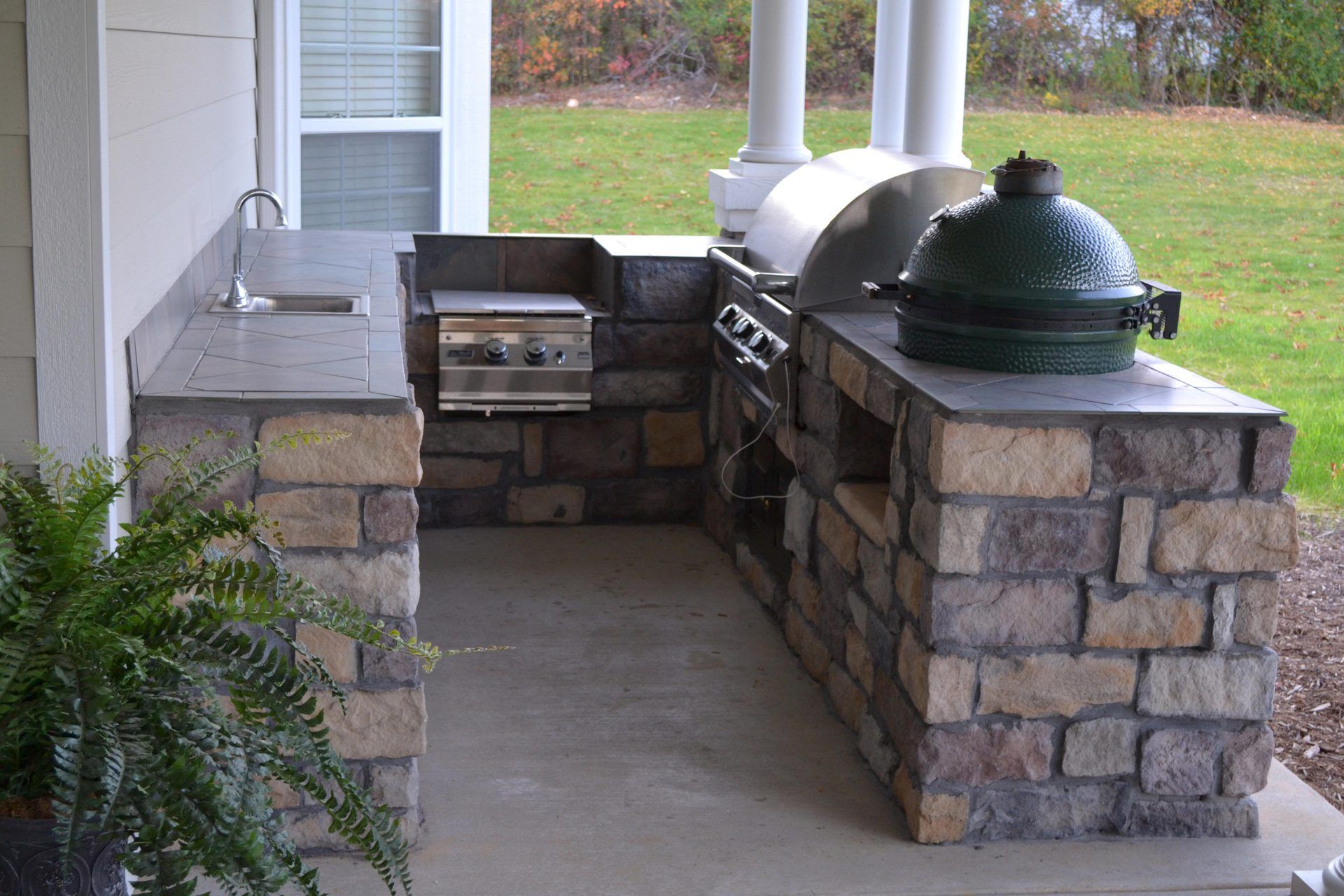 An outdoor kitchen with a green egg on top of it