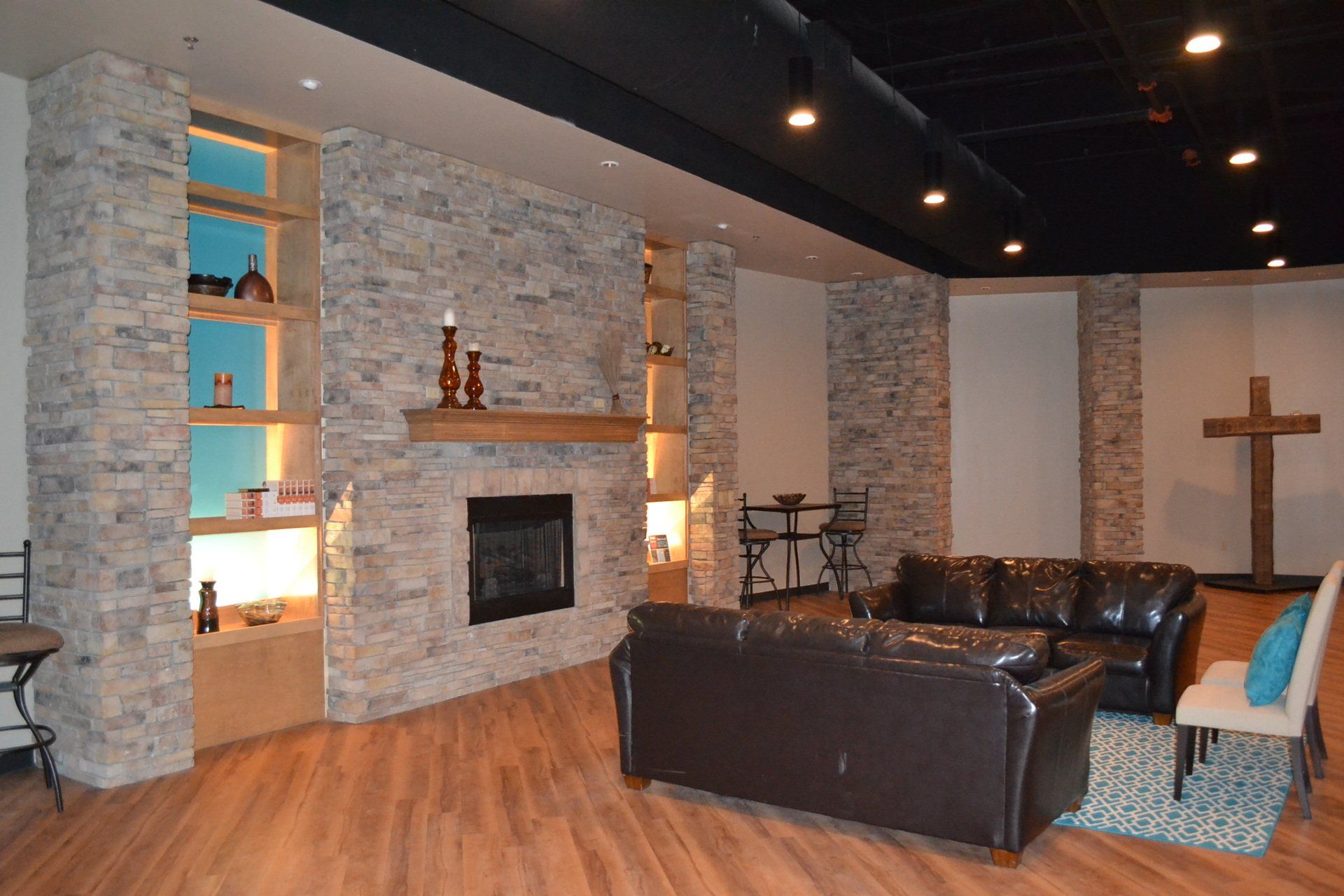 A living room with a couch a fireplace and a cross on the wall.