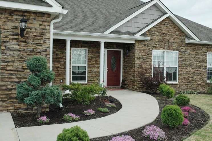 A stone house with a red door and a walkway leading to it
