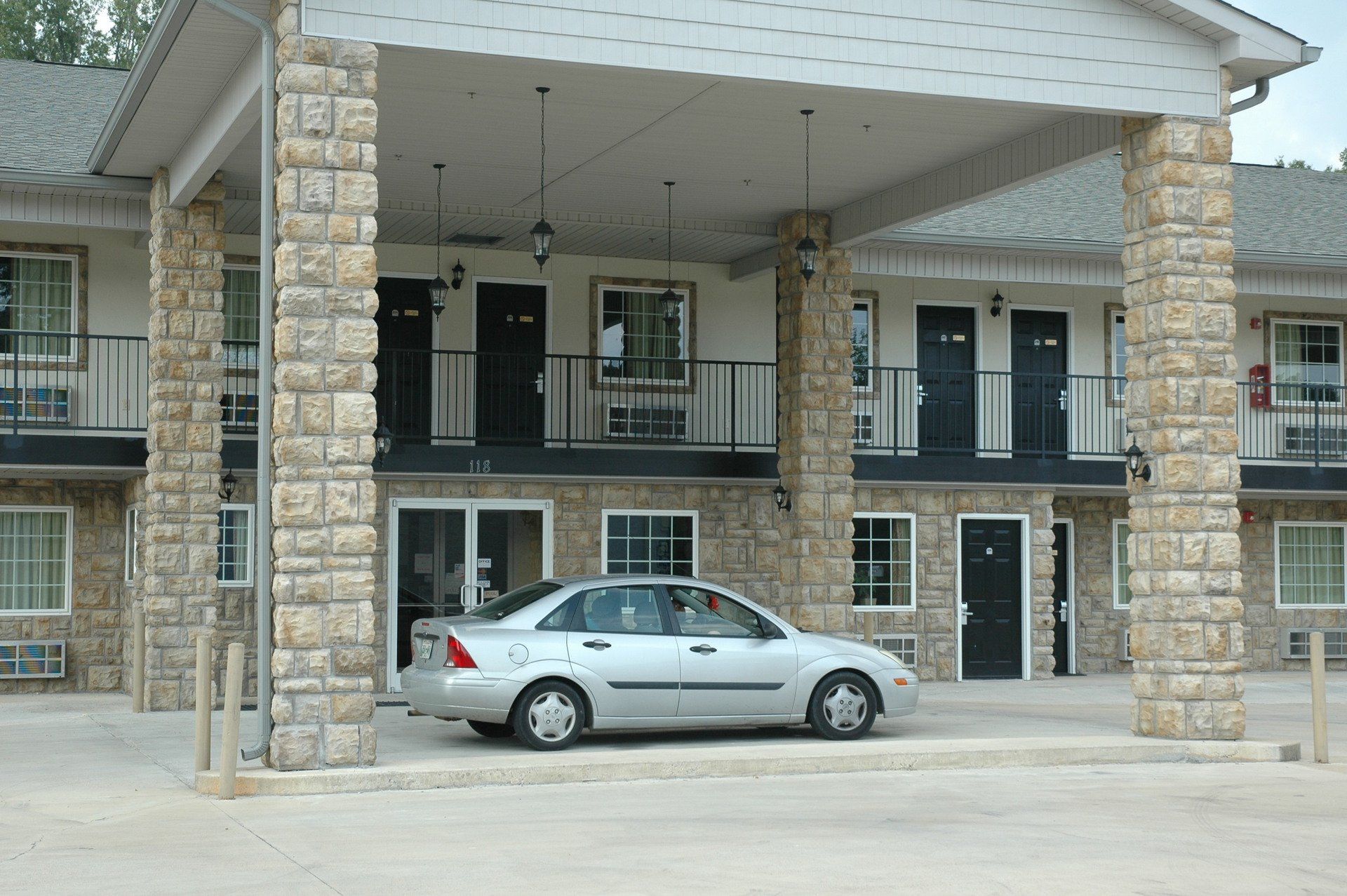 A silver car is parked in front of a hotel