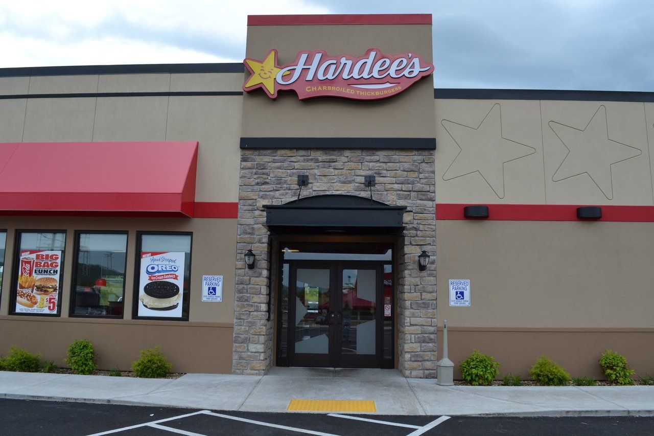 The front of a hardees restaurant with a red awning