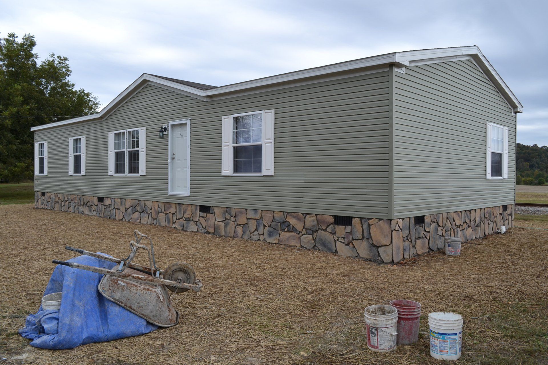 A mobile home is sitting in the middle of a dirt field.