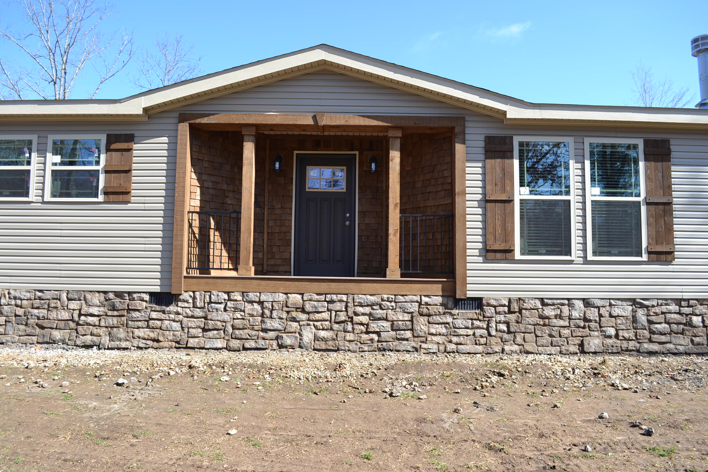 A mobile home with a porch and shutters on the windows