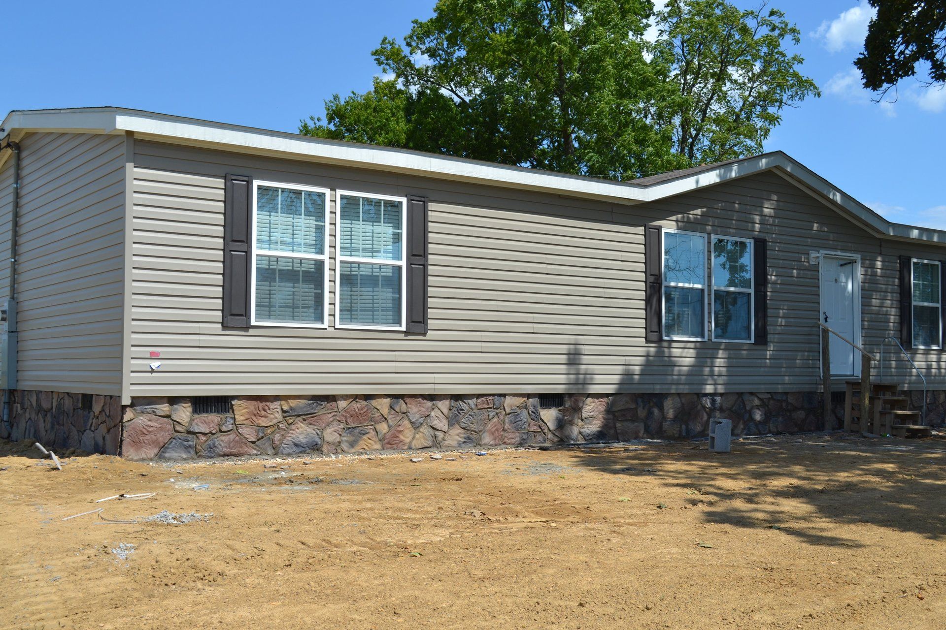 A mobile home is sitting in the middle of a dirt field.