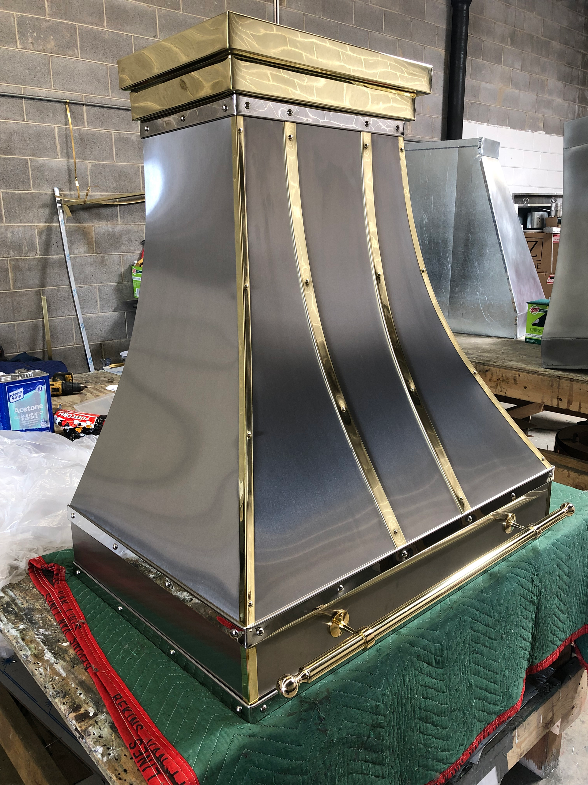 A stainless steel hood with gold trim is sitting on a table.