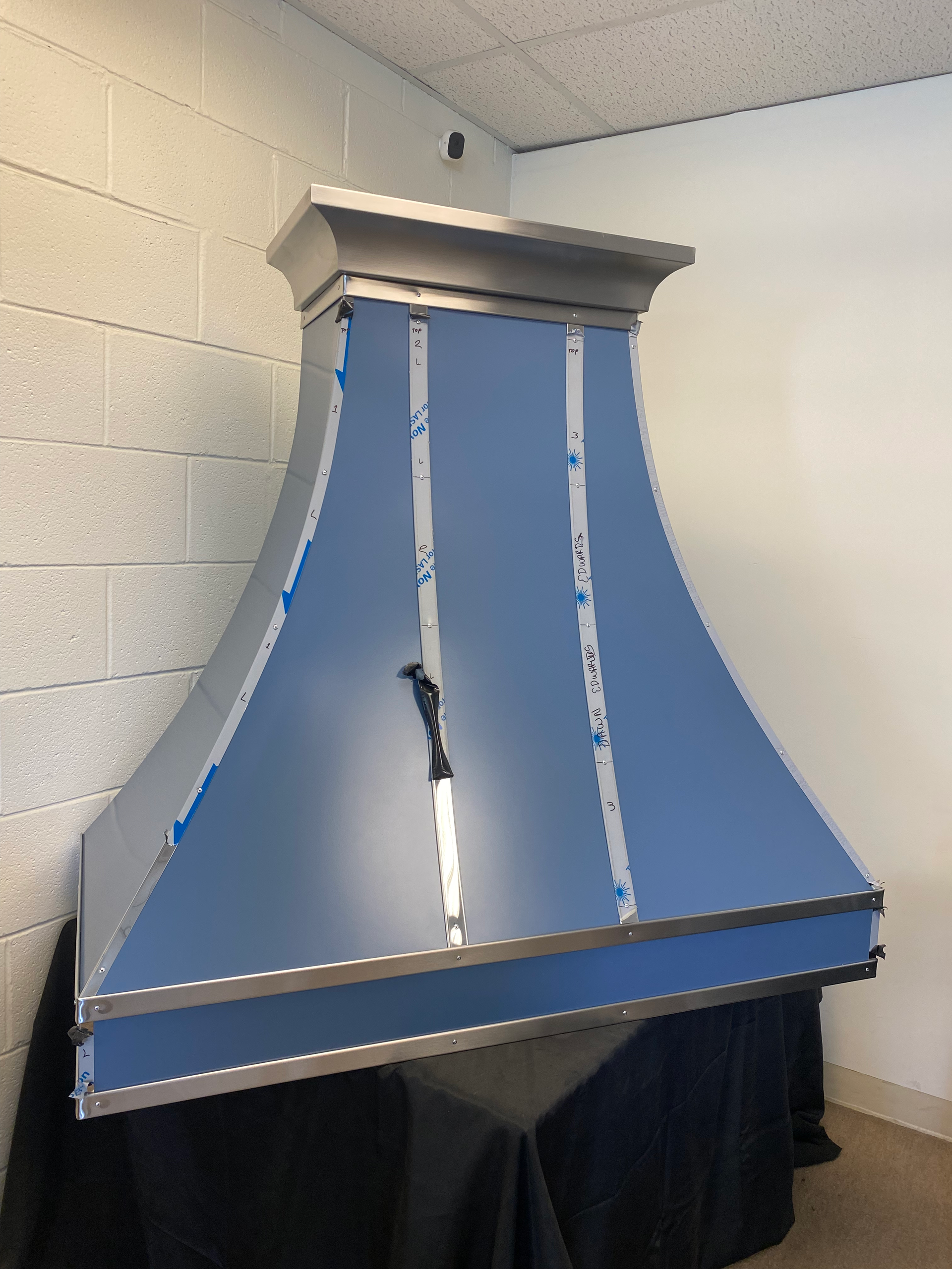 A blue hood is hanging from the ceiling in a room