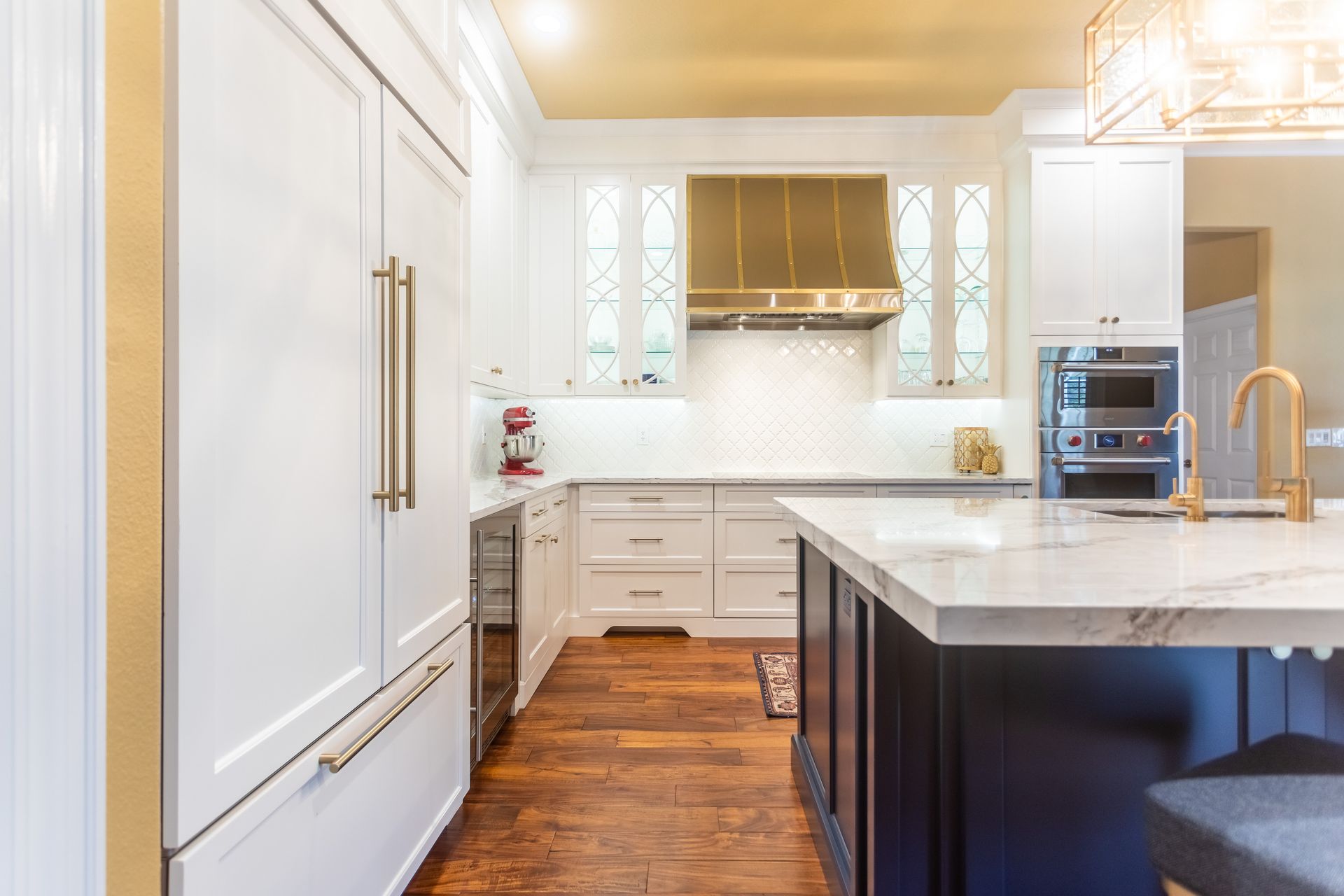 A kitchen with white cabinets , gold appliances , and a large island.