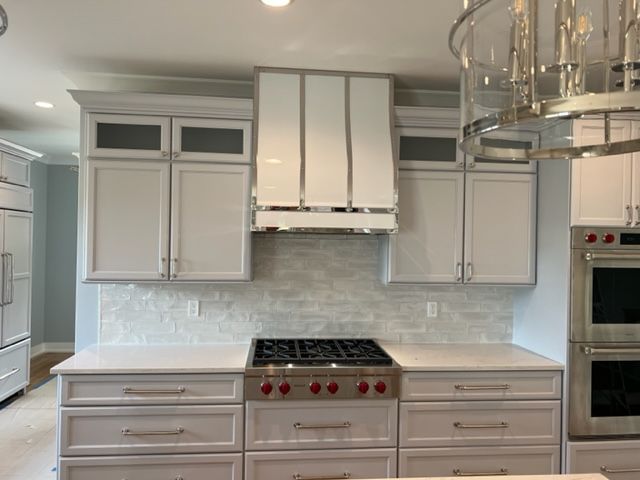 A kitchen with white cabinets and a stove top oven.