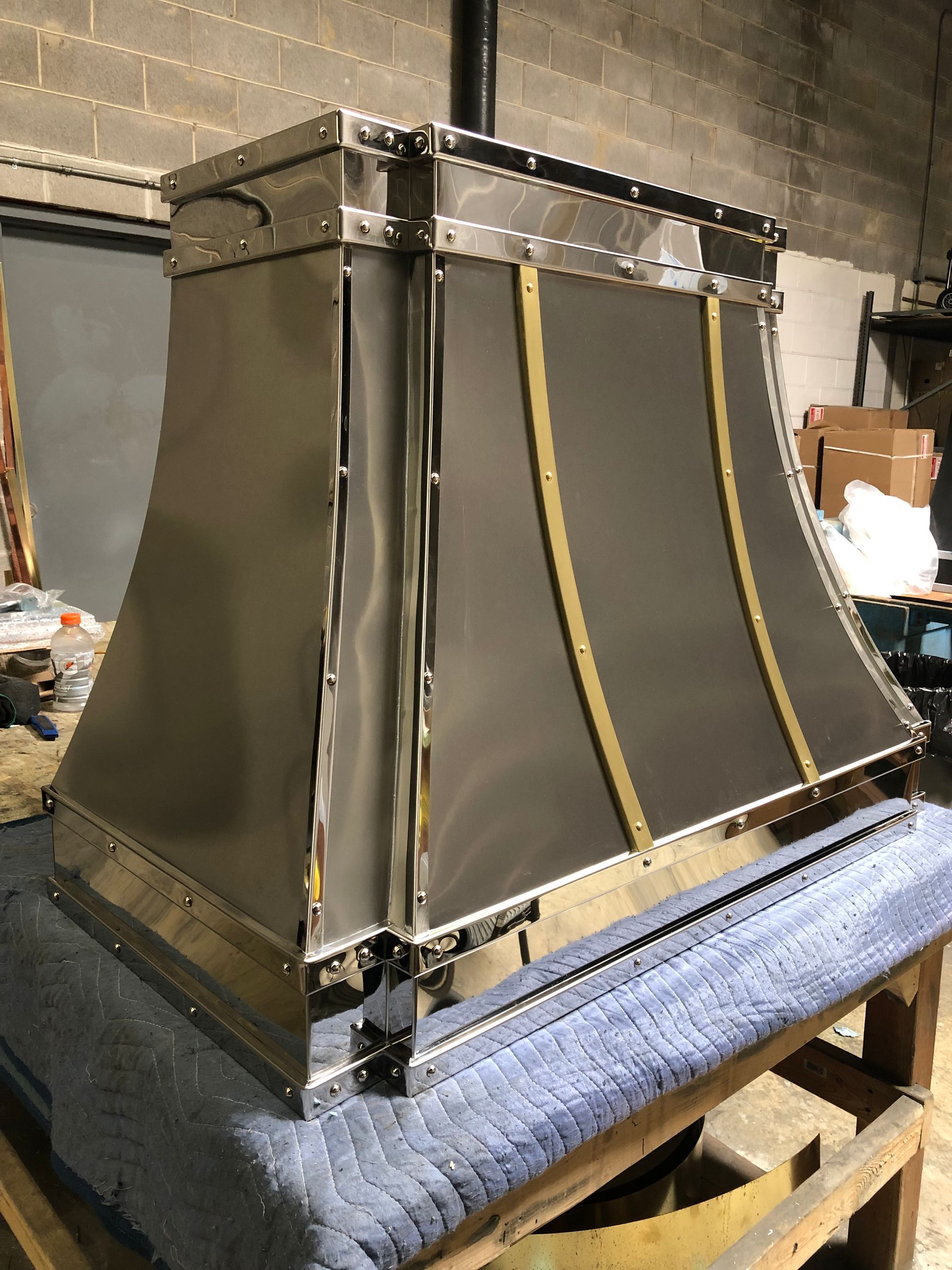 A stainless steel hood is sitting on top of a wooden table.