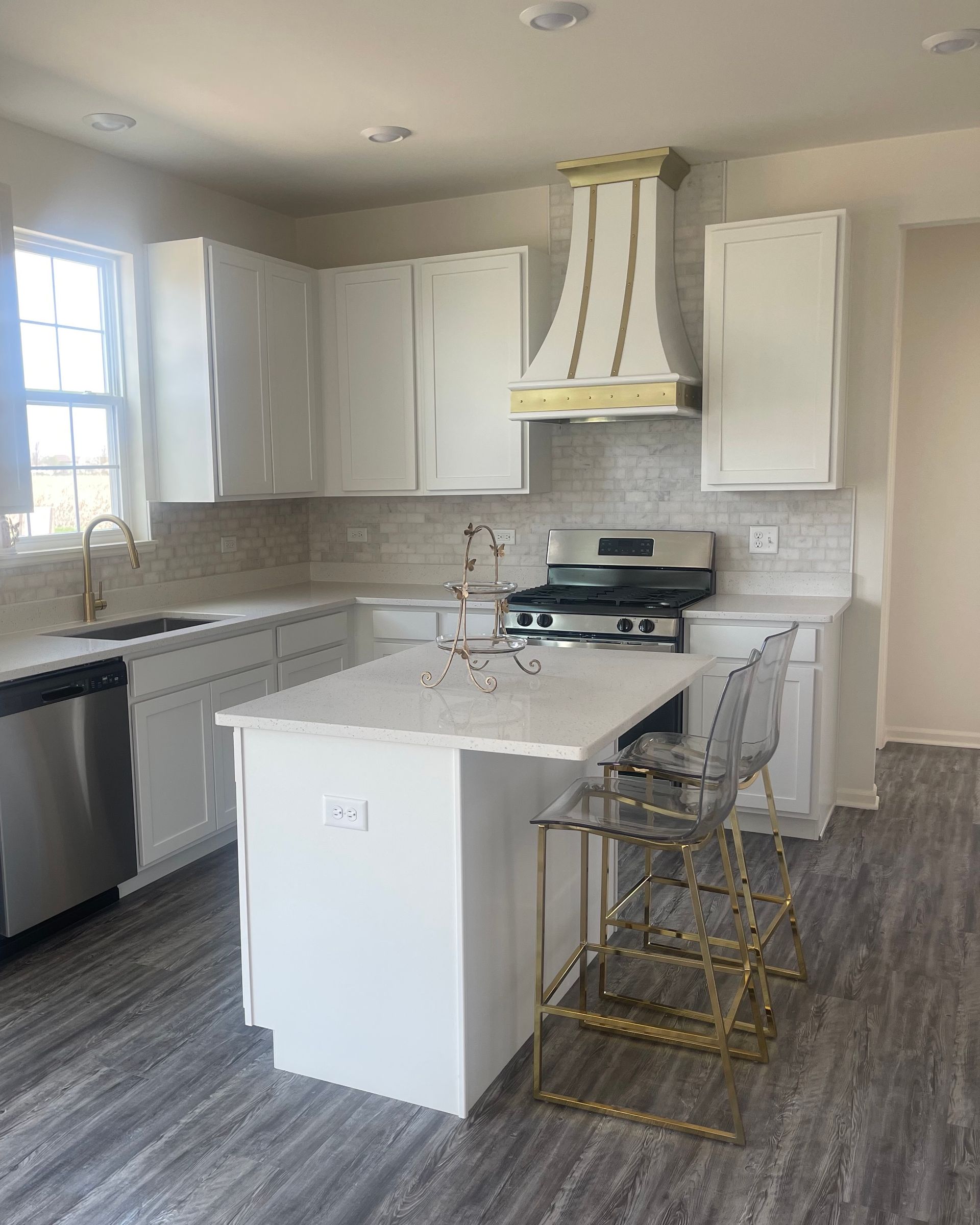 A kitchen with white cabinets , stainless steel appliances , and a large island.