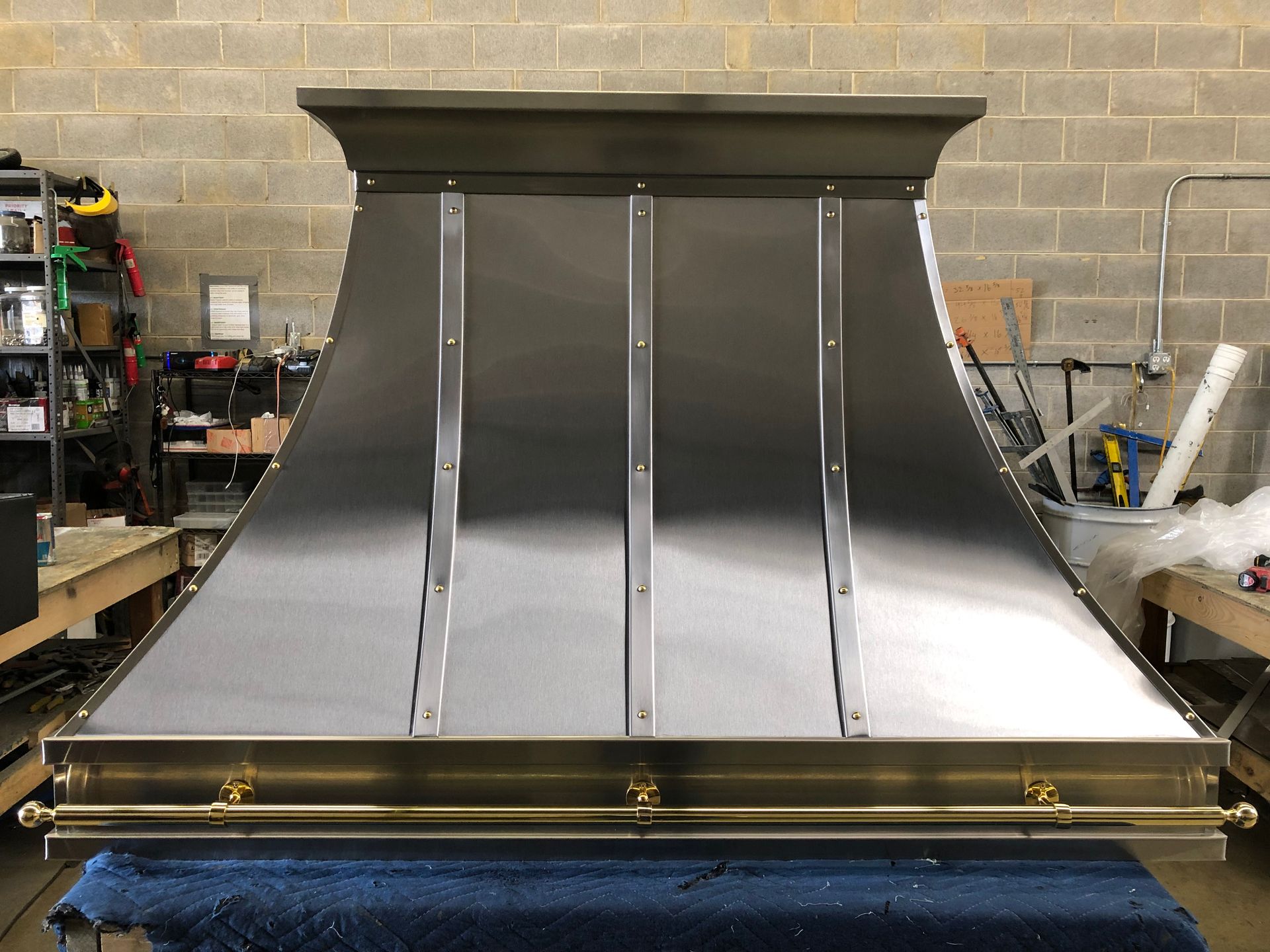 A stainless steel hood is sitting on a table in front of a brick wall.