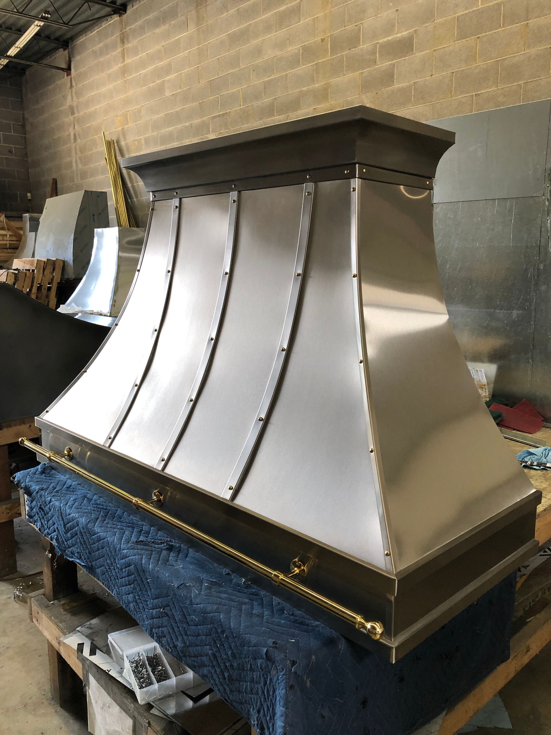 A large stainless steel hood is sitting on top of a wooden table.