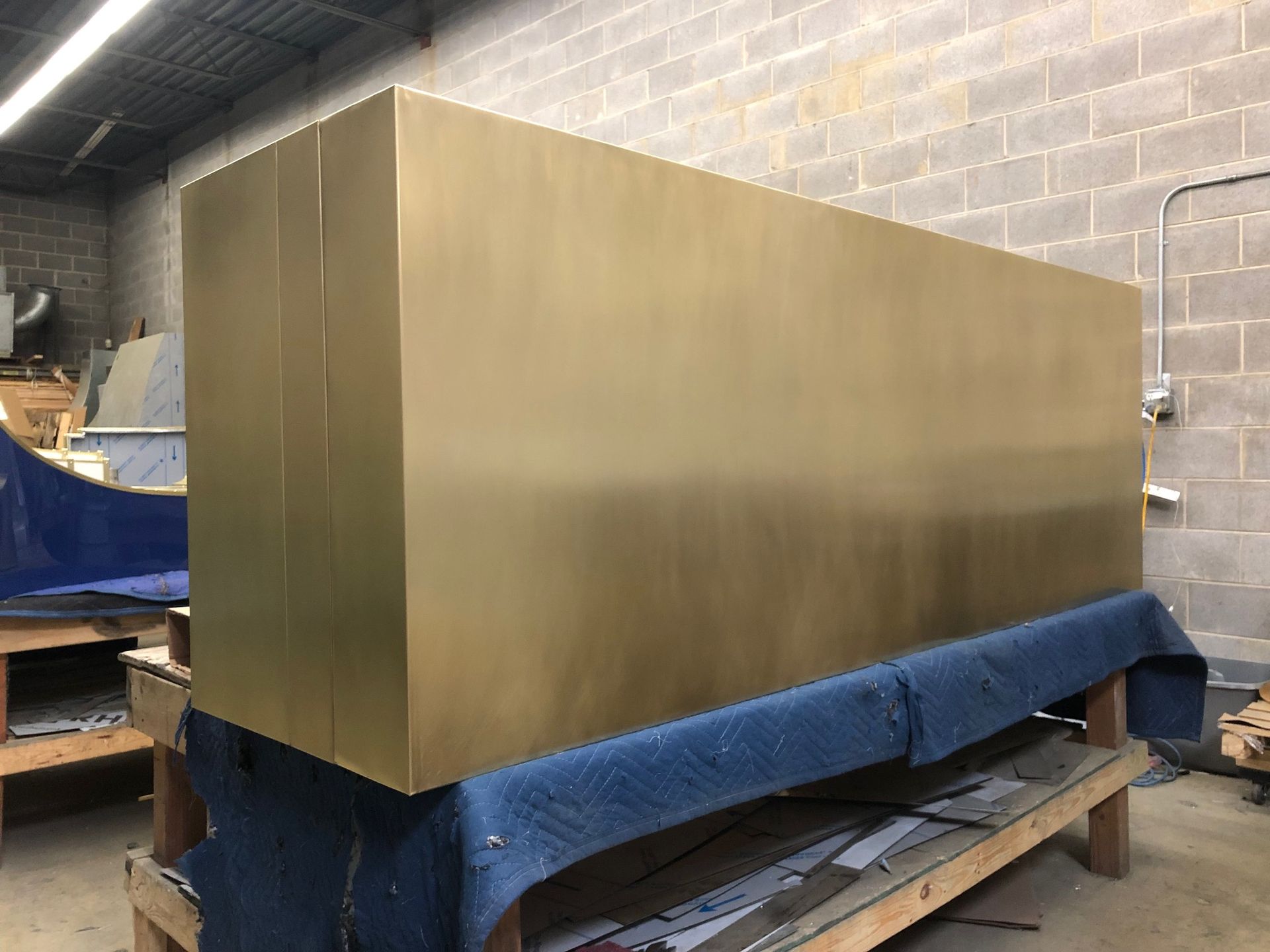 A large brass box is sitting on top of a wooden bench in a room.