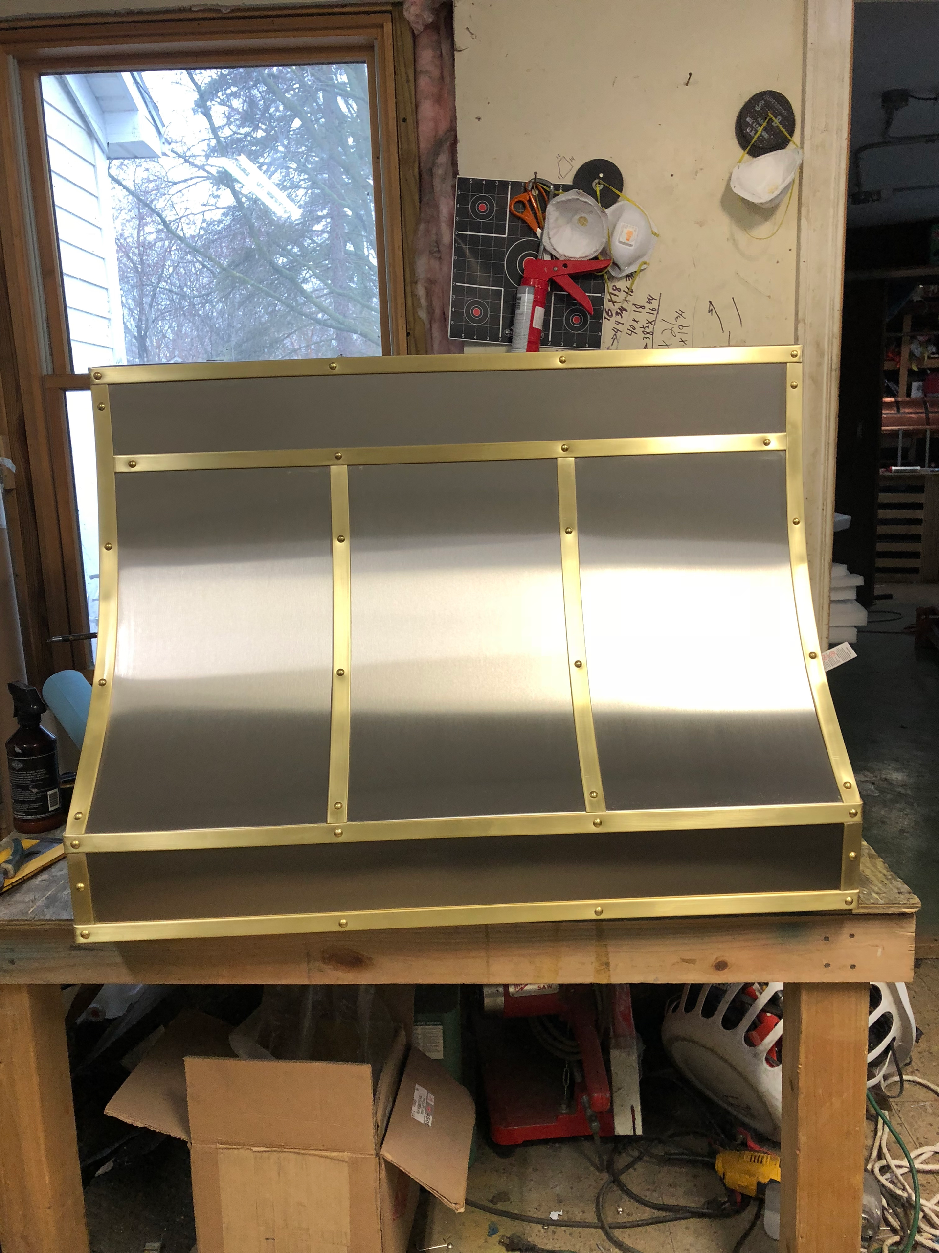 A stainless steel hood is sitting on top of a wooden table.