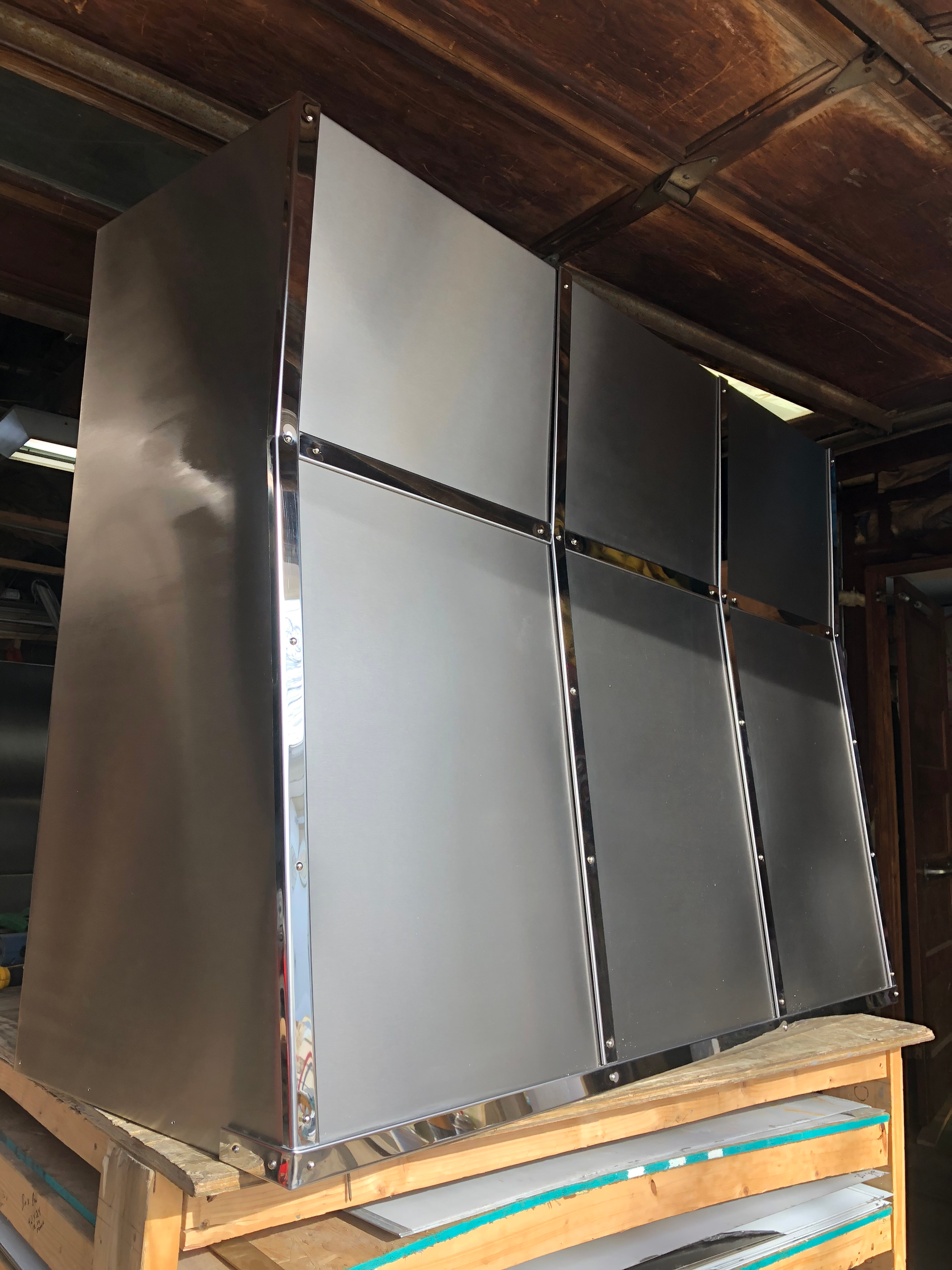 A stainless steel refrigerator is sitting on a wooden pallet