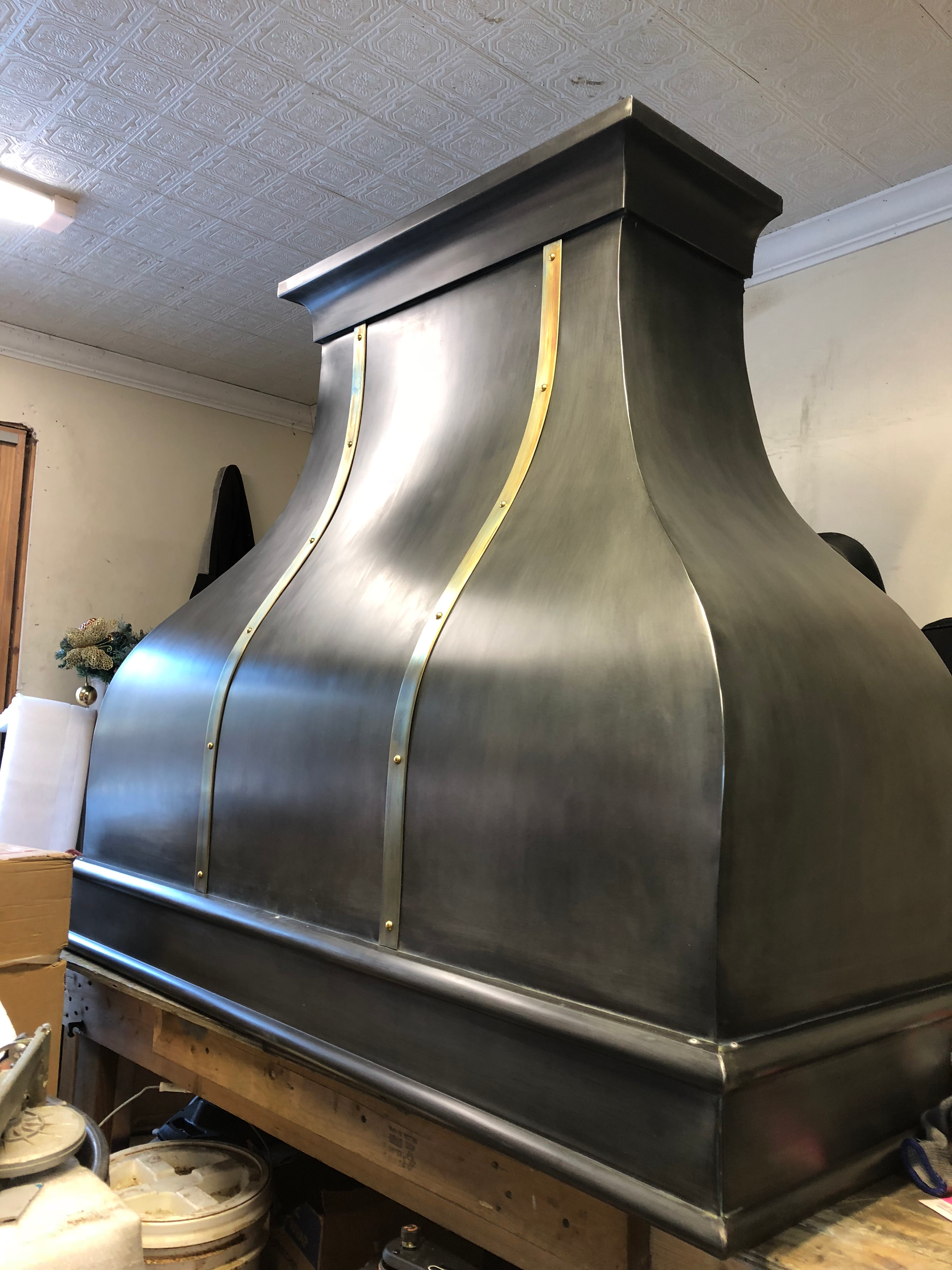 A large metal hood is sitting on top of a wooden table.