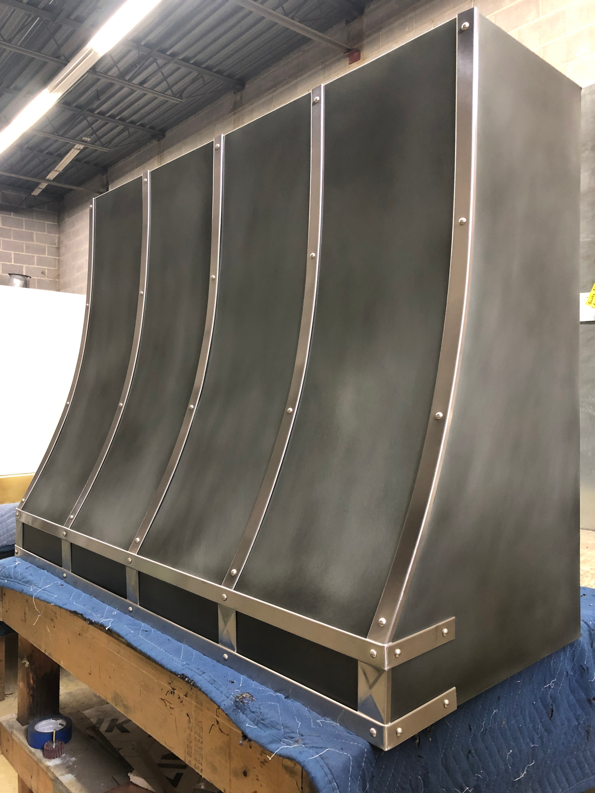 A stainless steel hood is sitting on top of a wooden table.