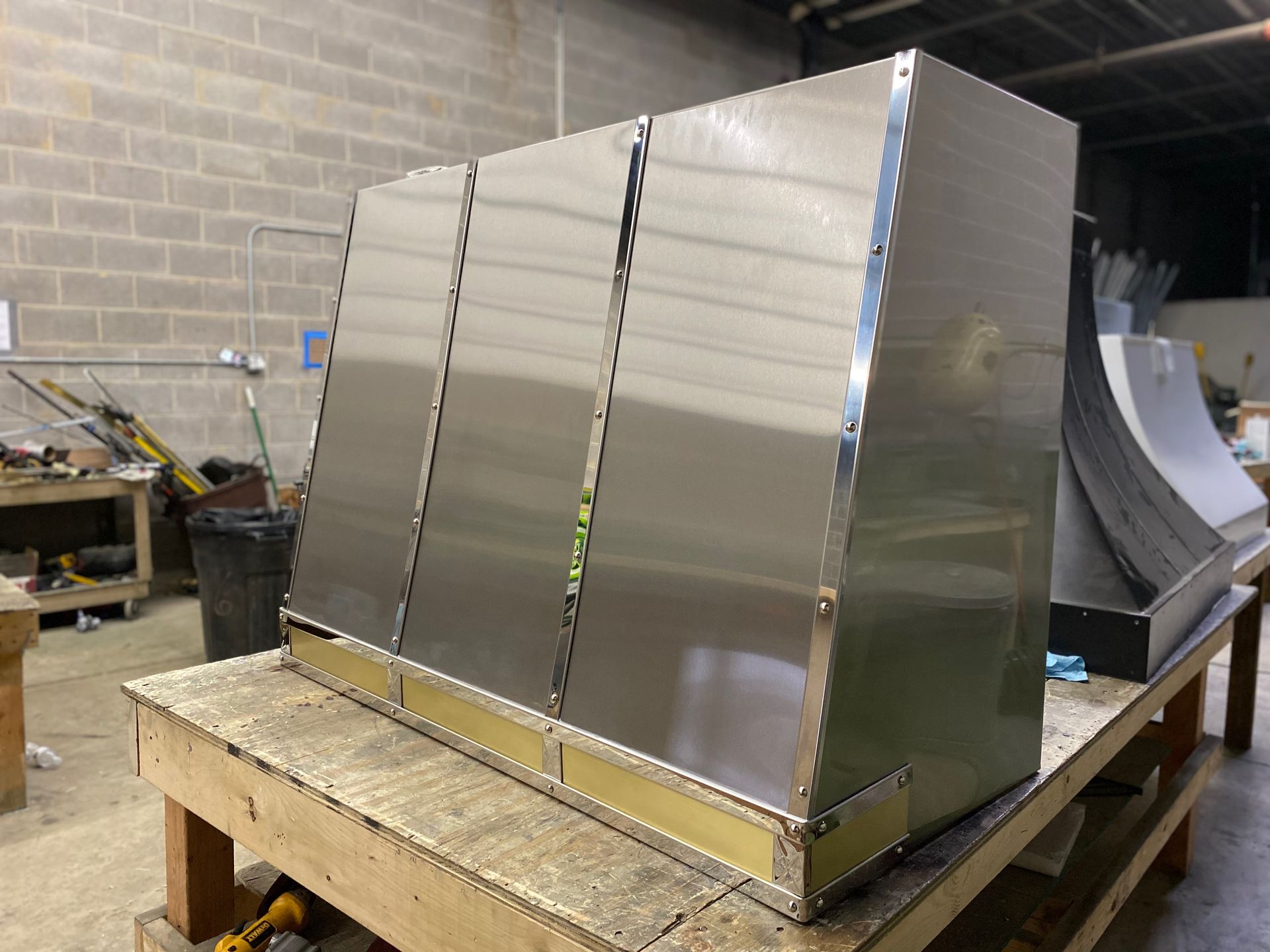 A stainless steel hood is sitting on top of a wooden table.