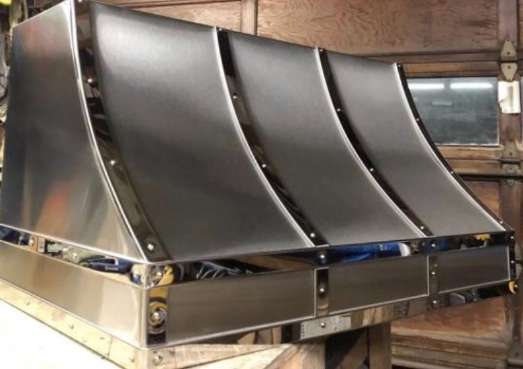 A stainless steel hood is sitting on a wooden table