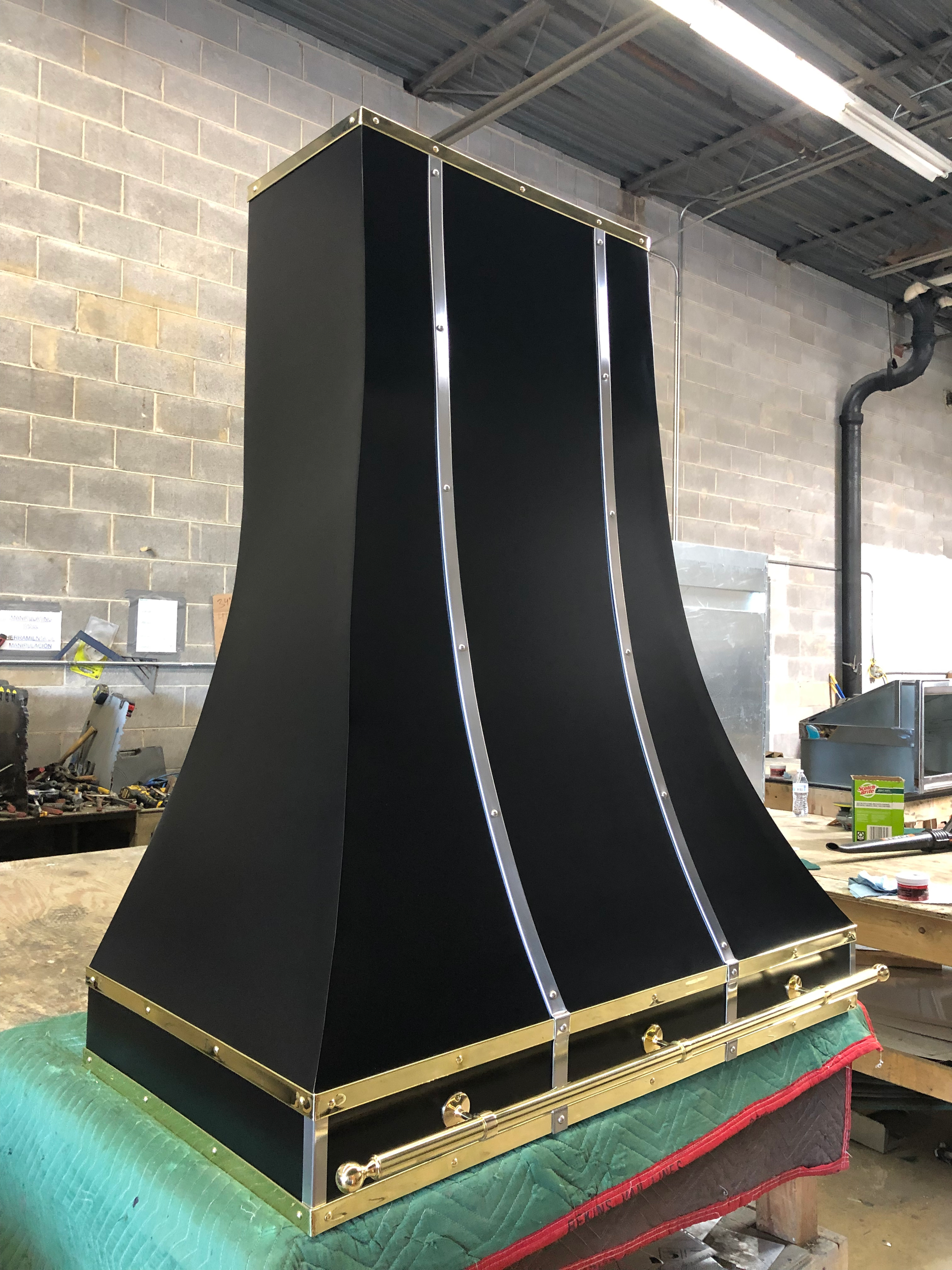 A black and gold hood is sitting on top of a green table.