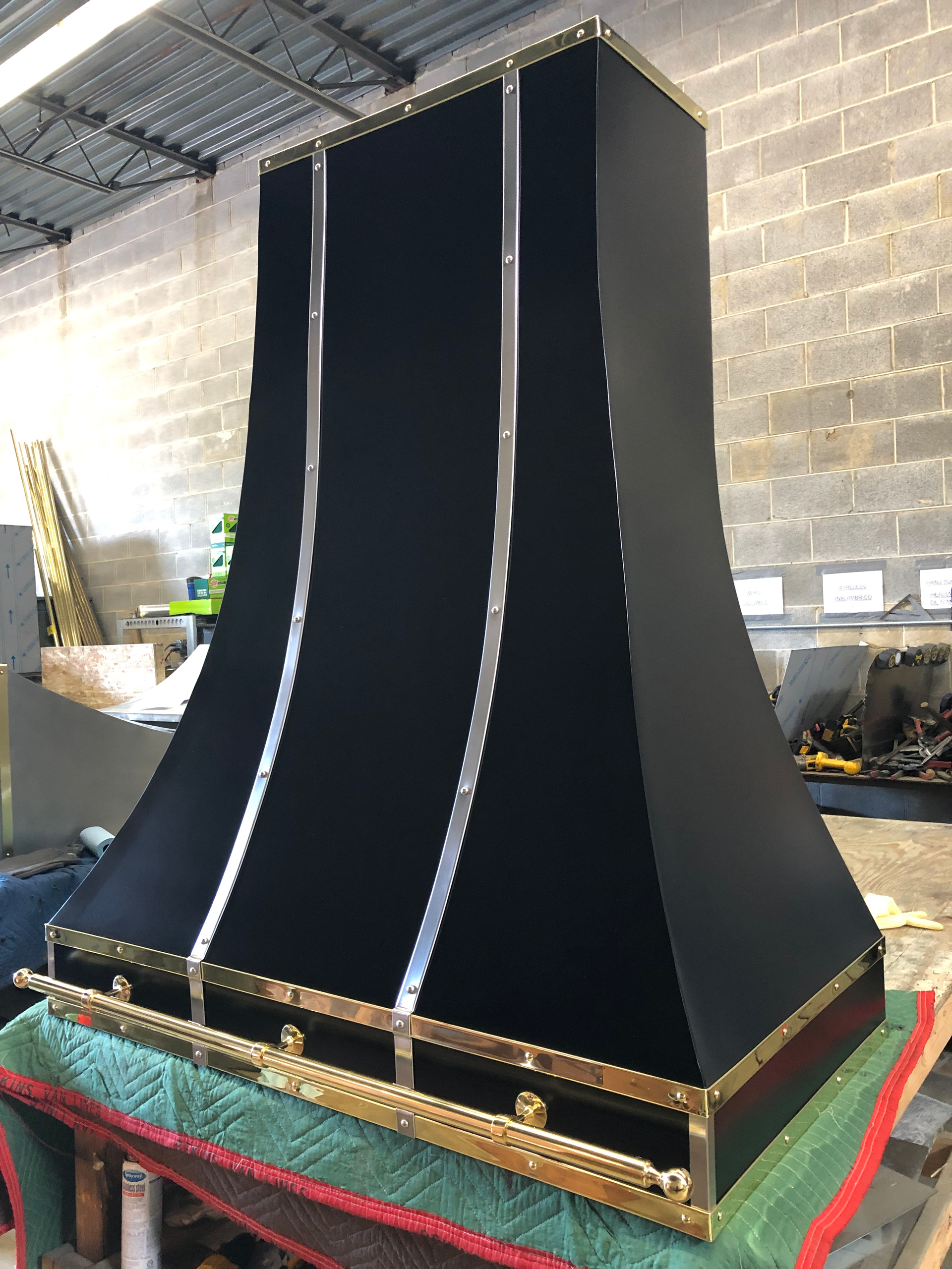 A black and gold hood is sitting on top of a green table.