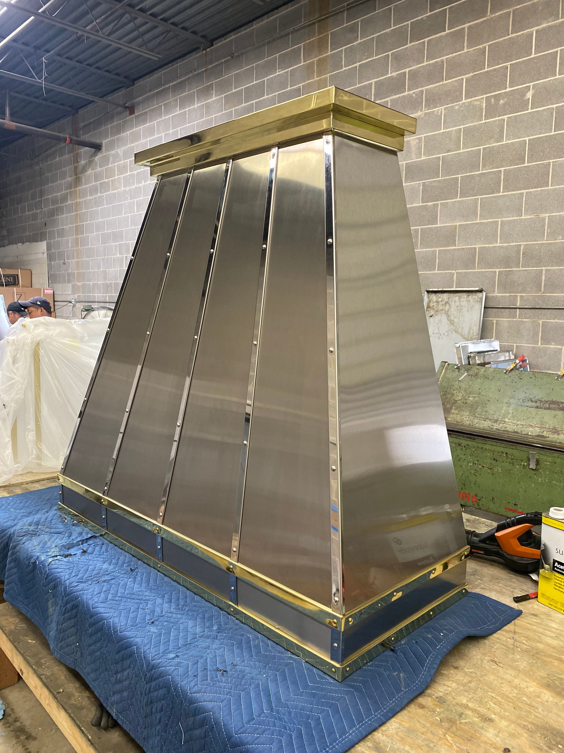 A stainless steel hood is sitting on top of a blue blanket in a room.