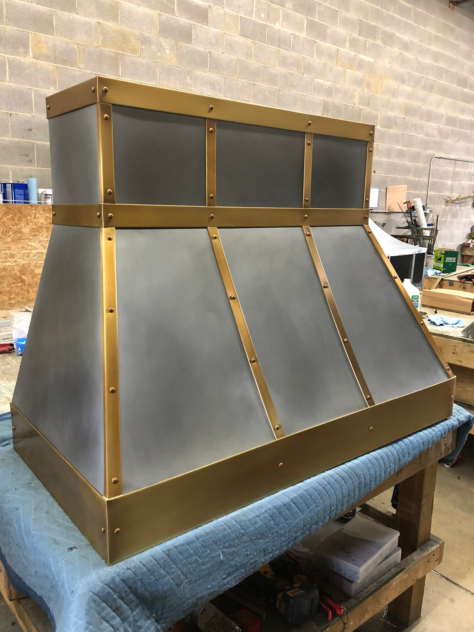 A brass and stainless steel hood is sitting on a table.