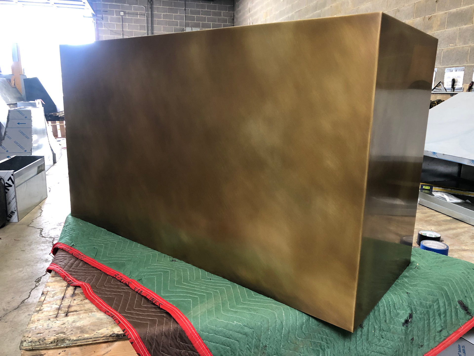 A large brass box is sitting on top of a green blanket on a table.