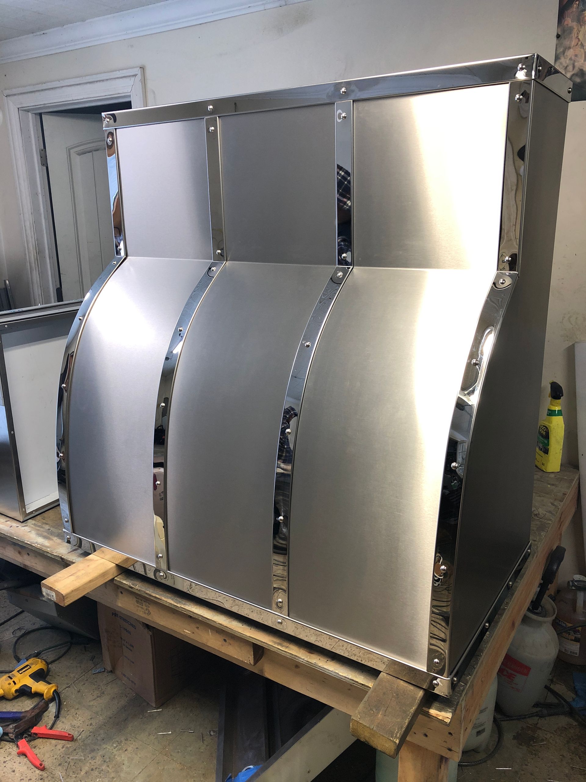 A stainless steel hood is sitting on top of a wooden table.