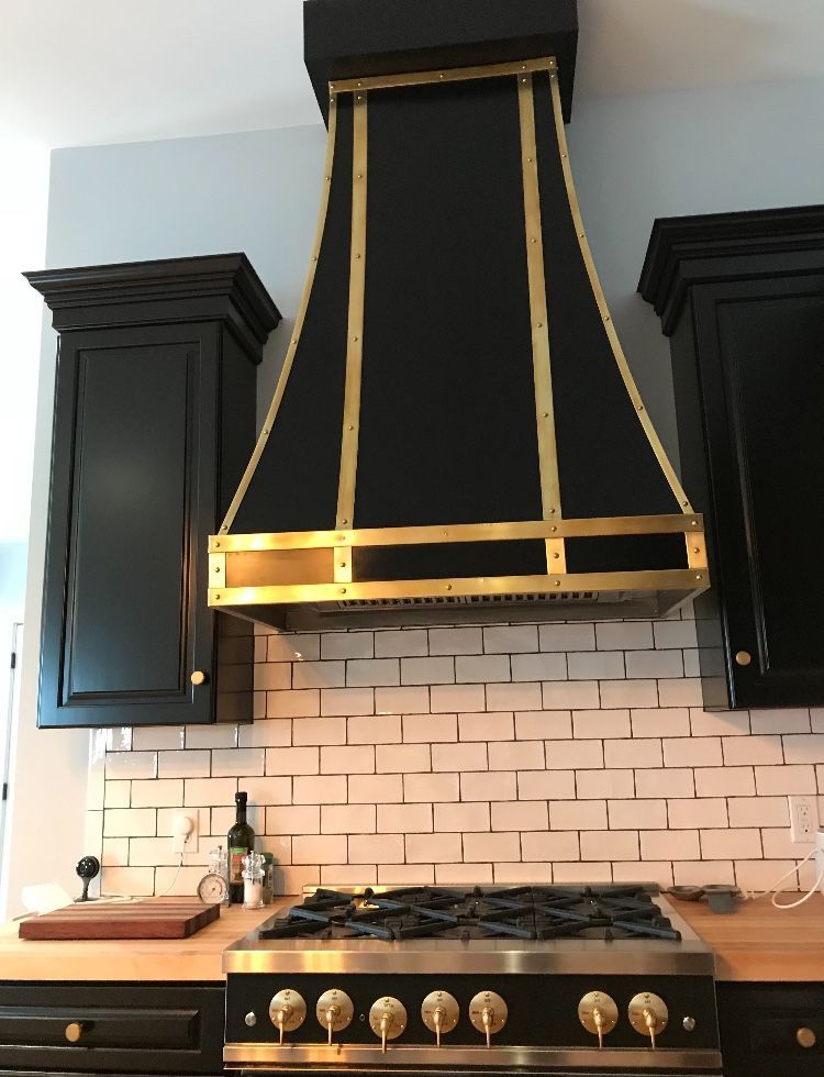 A kitchen with black cabinets and a black hood above the stove