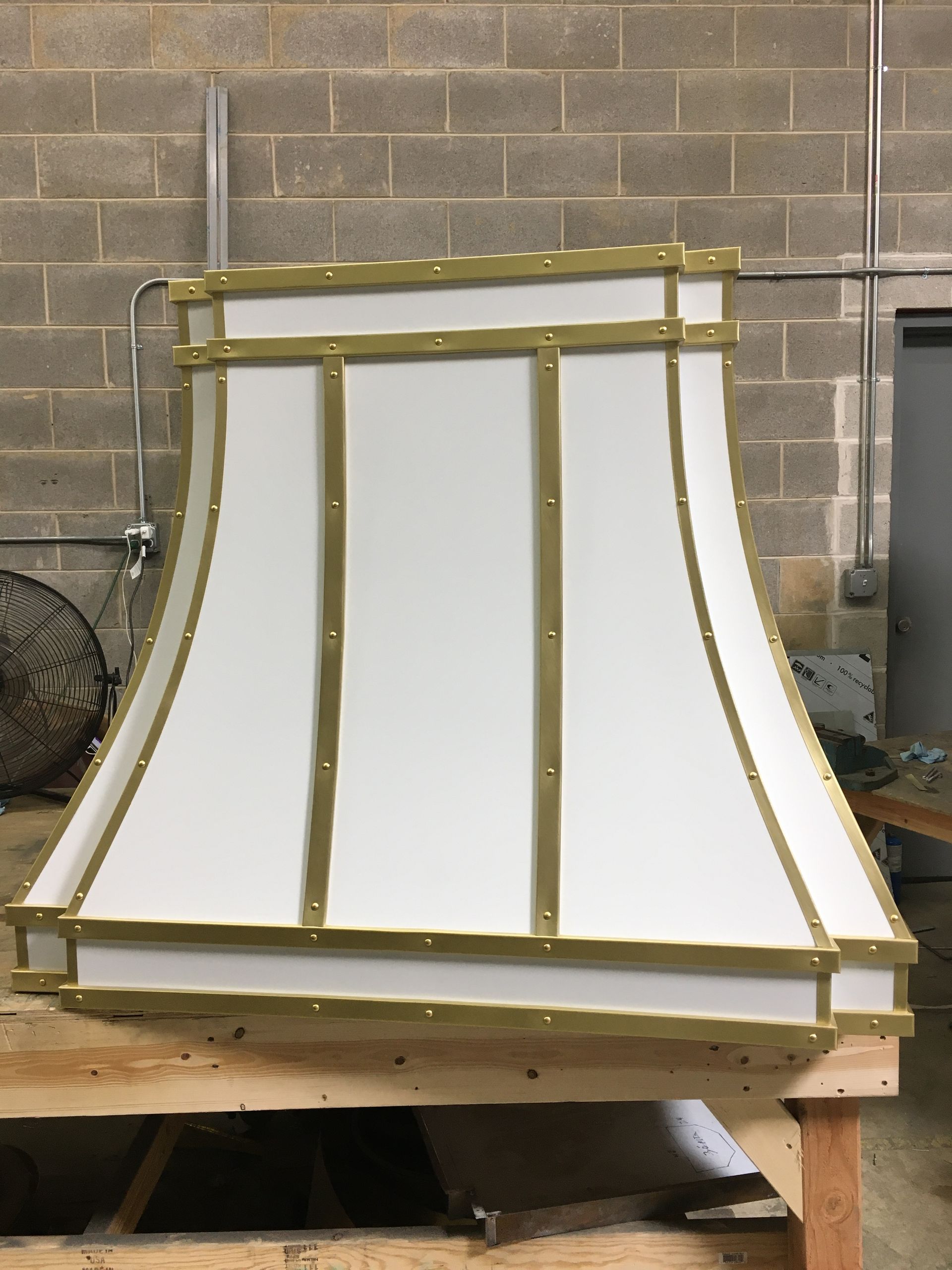 A white lamp shade with gold trim is sitting on a wooden table.