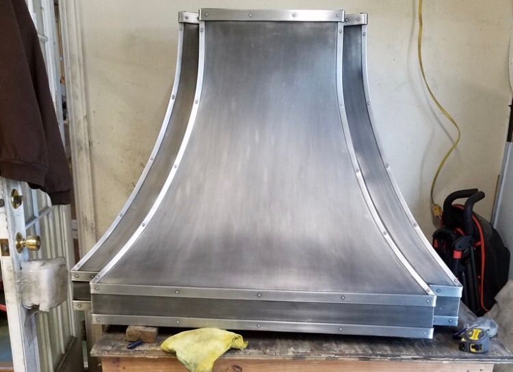 A stainless steel hood is sitting on a wooden table.