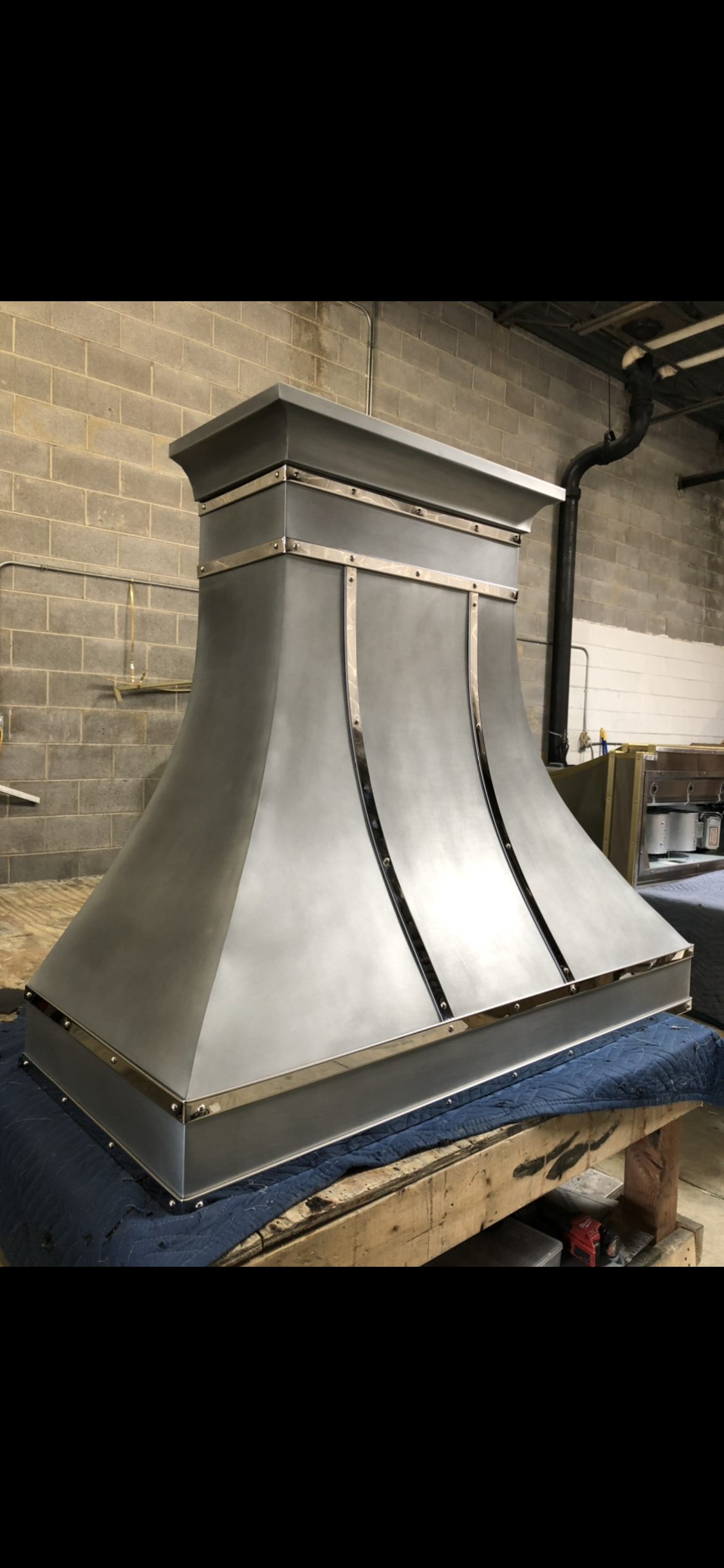 A stainless steel hood is sitting on top of a blue table.