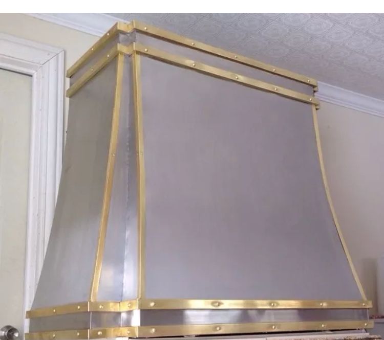 A stainless steel hood with gold trim is hanging from the ceiling