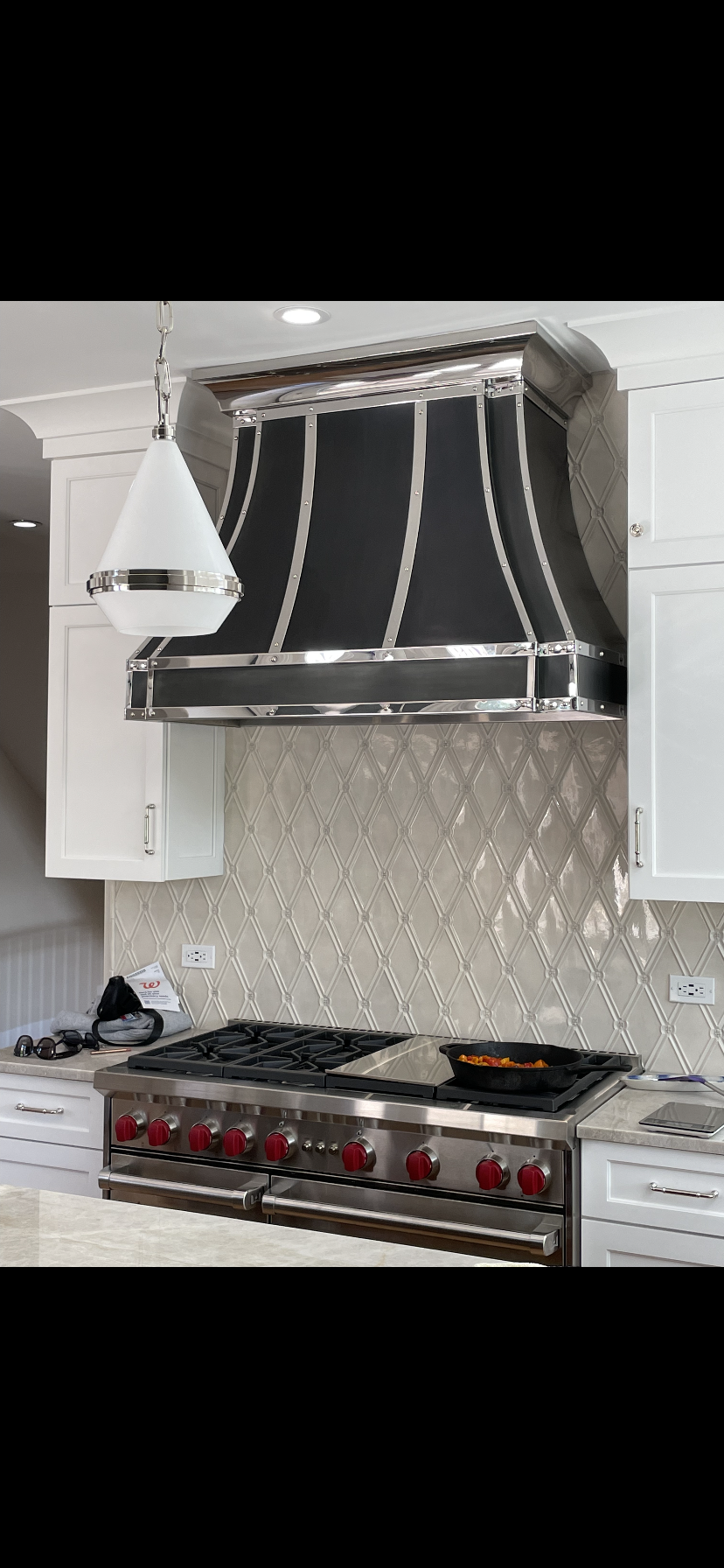 A kitchen with a stove and a hood above it.