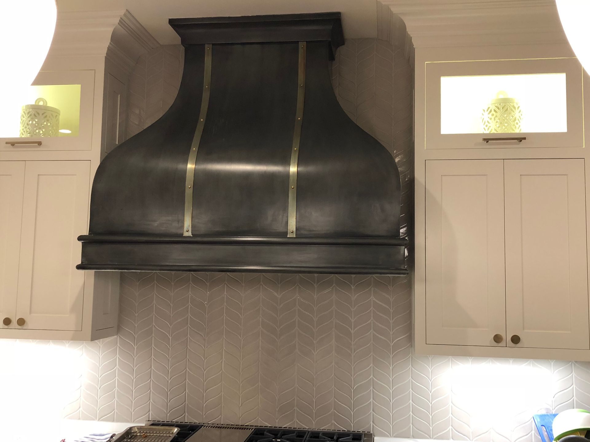 A kitchen with white cabinets and a black hood