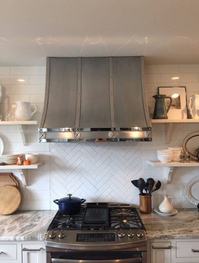 A kitchen with a stove and a hood above it.